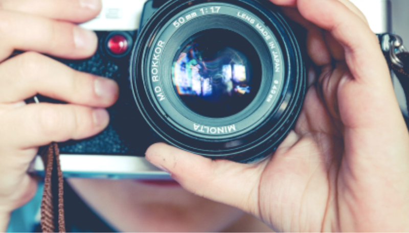 Ein Mensch schaut durch eine Kamera.