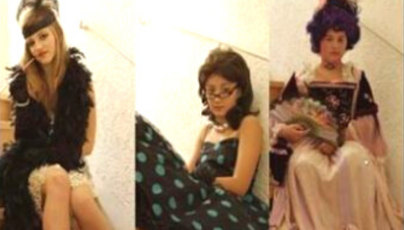 Ein Kind sitzt in einem historischen Kleid auf einer Treppe und blickt in die Kamera.