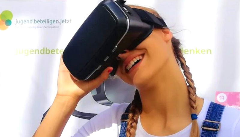 Person lächelt in die Kamera und trägt eine Virtual Reality Brille.