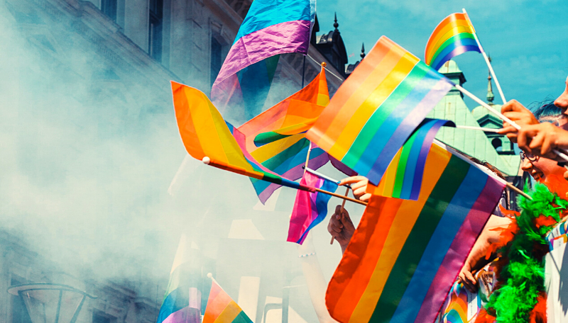 Mehrere Regenbogenflaggen wehen im Wind.