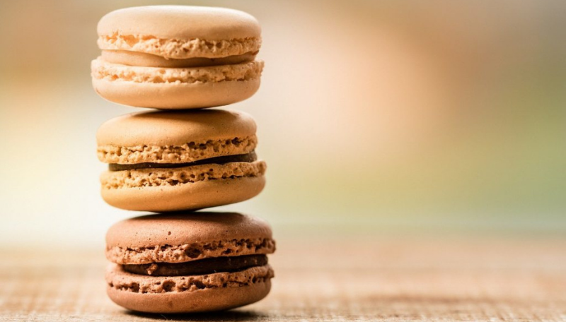 Drei braune Macarons die aufeinander gestappelt sind.