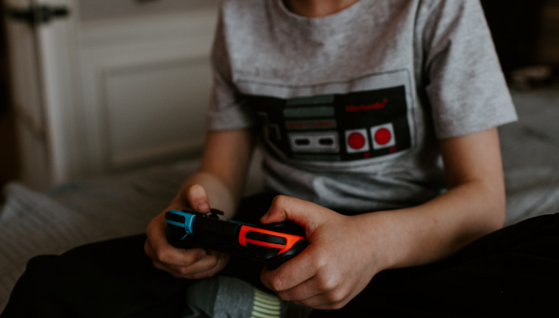 Ein Kind sitzt im Schneidersitz und hält einen Controller in beiden Händen.