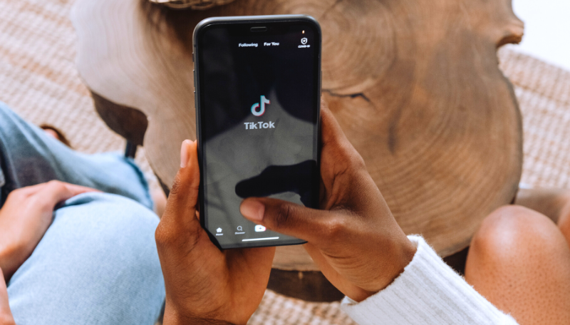 Zwei Hände halten ein Smartphone, auf dem gerade die App Tiktok geöffnet wird.